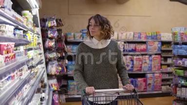 食品，健康概念-在超市里的女人站在冰箱货架前，选择买一瓶